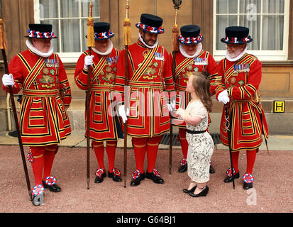 Paralympische Schwimmerin Ellie Simmonds mit Mitgliedern der Yeoman of the Guards, nachdem sie während einer Investiturfeier im Buckingham Palace im Zentrum Londons ihre OBE-Medaille vom Prince of Wales erhalten hatte. Stockfoto