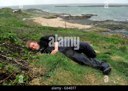 National Trust Ranger will Scott erreicht seine Hand in einem Papageientaucher-Bau auf Inner Farne auf den Farne-Inseln, während die Volkszählung der National Trust Puffin 2013 beginnt. Stockfoto