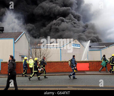 Streikende Feuerwehrleute aus Willenhall, die ihre Streikposten durchbrochen haben, um am ersten Tag des nationalen Feuerwehrstreiks an einem massiven Brand in einer stillsitzenden Kunststofffabrik in West Bromwich teilzunehmen, verlassen den Tatort, nachdem sichergestellt wurde, dass dort niemand gefangen war. Stockfoto
