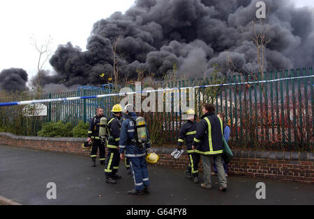 Streikende Feuerwehrleute aus Willenhall, die ihre Streikposten durchbrochen haben, um am ersten Tag des nationalen Feuerwehrstreiks an einem massiven Brand in einer stillsitzenden Kunststofffabrik in West Bromwich teilzunehmen, verlassen den Tatort, nachdem sichergestellt wurde, dass dort niemand gefangen war. Stockfoto