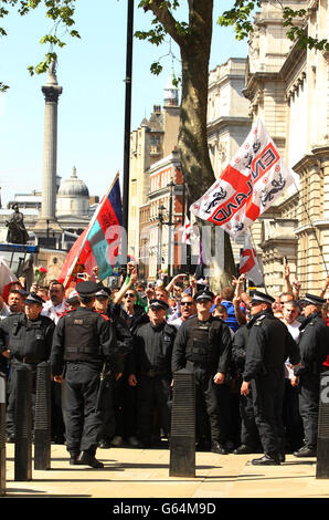 Polizeibeamte stehen vor EDL-Demonstranten in Whitehall nahe der Downing Street in London. Stockfoto