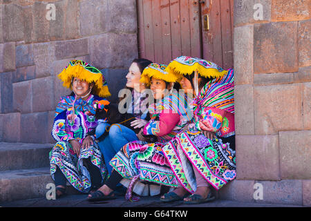 Drei peruanische Mädchen posiert mit einem westlichen Touristen in der Stadt Cusco Stockfoto