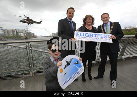 Ein irisches Luftkorps Agusta Westland AW139 fliegt über den Fluss Liffey in Dublin, mit (im Vordergrund) Robert Kennedy, 6 und (von links nach rechts) Verkehrsminister Leo Varadkar, Die Vorsitzende der irischen Luftfahrtbehörde, Anne Nolan, und der Bürgermeister von Dublin, Naoise O Muiri, während einer Fotozelle für das Flightfest 2013, bei der Dutzende von Flugzeugen über das Stadtzentrum fliegen werden. Stockfoto