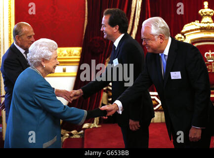 Queen Elizabeth II begrüßt den Sender Martyn Lewis (rechts) bei einem Empfang zum zehnten Jahrestag des Queen's Award for Voluntary Service im St. James' Palace, London. Stockfoto