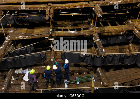 Restauratoren stehen im Inneren des Rumpfes des Tudor-Kriegsschiffs, der Mary Rose, im neuen Mary Rose Museum, das Ende Mai im Portsmouth Historic Dockyard in Hampshire eröffnet wird. Stockfoto