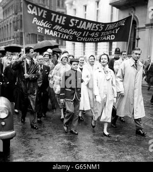 Vor einem Banner treten der Schauspieler Sir Laurence Olivier und seine Schauspielerin Frau Vivien Leigh hervor. Sie sind auf dem St. James's Square in London zu sehen, als sie eine Prozession durch den Regen vom St. James's Theatre zum Innenhof der St. Martin-in-the-Fields Church, Trafalgar Square, geleitet haben, wo Reden gehalten werden sollten. Der öffentliche marsch und das Treffen wurden von British Actors' Equity aufgerufen, um gegen die Schließung des St. James's Theatre zu protestieren und die Aufmerksamkeit auf die fortgesetzte Schließung von Theatern in ganz Großbritannien zu lenken. Stockfoto