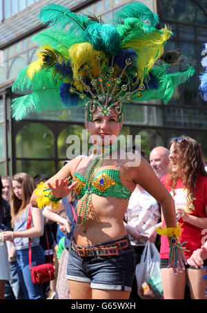 Ein Mitglied der Edinburgh Samba-Gruppe, als sie an der Mardis Gras Parade teilnehmen, die von Menschenmassen auf der Byres Road in Glasgow beobachtet wird. Rund 600 Teilnehmer nahmen an der Straßenparade Teil, um das West End Festival zu beginnen, an dem rund 70,000 Menschen teilnehmen werden. Stockfoto