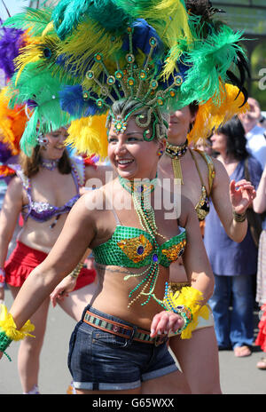 Ein Mitglied der Edinburgh Samba-Gruppe, als sie an der Mardis Gras Parade teilnehmen, die von Menschenmassen auf der Byres Road in Glasgow beobachtet wird. Rund 600 Teilnehmer nahmen an der Straßenparade Teil, um das West End Festival zu beginnen, an dem rund 70,000 Menschen teilnehmen werden. Stockfoto