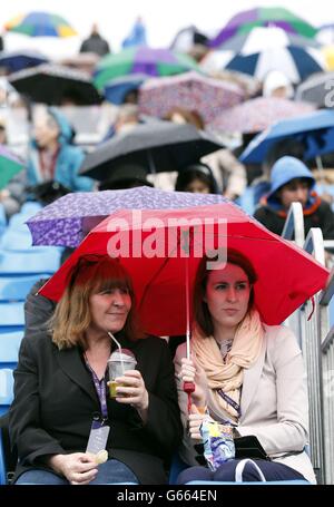 Die Zuschauer schützen sich bei einer Regenverzögerung im Finale der AEGON Championships im Queen's Club, London, unter Regenschirmen. Stockfoto