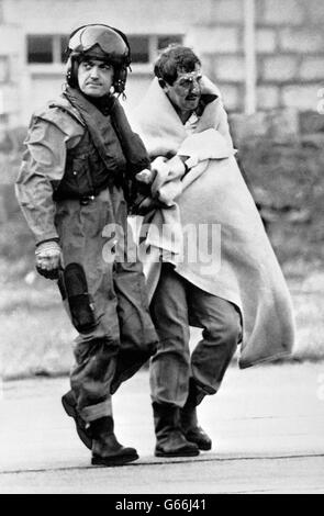 Royal Air Force Air Load Master Bob Pountney hilft einem Überlebenden bei der Ankunft in Aberdeen Royal Infirmary nach der Explosionskatastrophe auf der Nordsee-Ölförderplattform Piper Alpha. Stockfoto