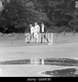 (l-r) Max Faulkner, Bernard Hunt und L Platts gehen auf dem wasserdurchlaserten Moor Park Course, wo sie beim Esso Golden Professional Match Play Turnier spielten. Stockfoto