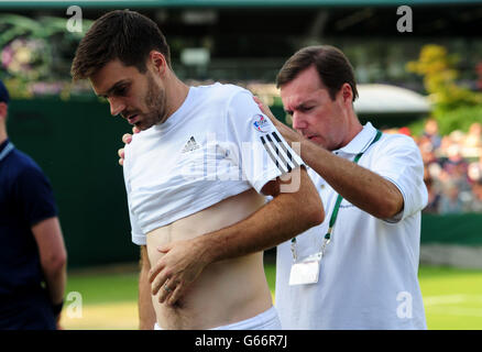 Der britische Colin Fleming wird in seinem Doppelspiel mit Jonathan Marray gegen die Slowaken Martin Klizan und Igor Zelenay am dritten Tag der Wimbledon Championships beim All England Lawn Tennis and Croquet Club in Wimbledon behandelt. Stockfoto