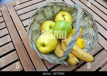 Zuckerrohr-Korb Kunsthandwerk mit Obst, Äpfel und Bananen auf Holztisch Stockfoto