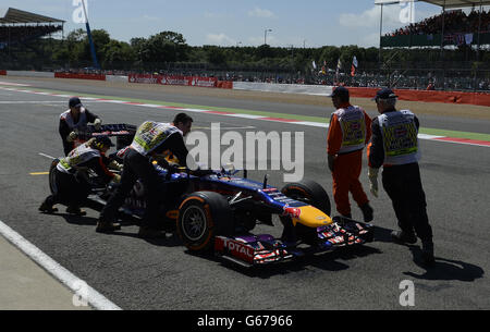 Der Red Bull Formel-1-Fahrer Sebastian Vettel wird von den Marschalls in die Box geschoben, nachdem er beim British Grand Prix von Santander 2013 auf dem Silverstone Circuit in Towcester angehalten hat. Stockfoto