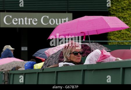 Am achten Tag der Wimbledon Championships im All England Lawn Tennis und Croquet Club, Wimbledon, schützen sich Fans vor Regen. Stockfoto