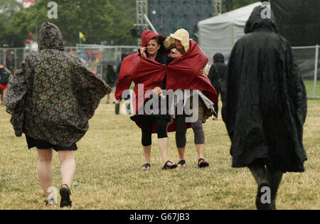 Glastonbury Festival 2013 - Tag 2. Festivalbesucher bei einem Regenschauer beim Glastonbury Festival auf der Worthy Farm in Somerset. Stockfoto