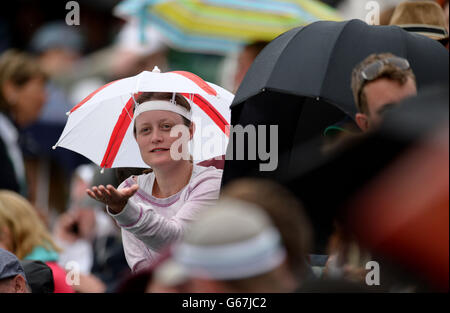 Am vierten Tag der Wimbledon Championships am All England Lawn Tennis und Croquet Club in Wimbledon schützen sich Fans vor dem Regen auf dem Platz zwei. Stockfoto