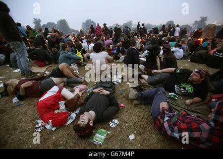 Festival-Besucher warten auf Sonnenaufgang am Stone Circle, beim Glastonbury Festival, Worthy Farm in Somerset. Stockfoto