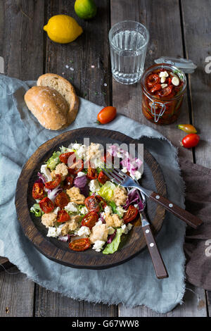 Gesunde traditionelle italienische Mahlzeit: Panzanella Salat mit Sonne getrockneten Tomaten, grüner Blattsalat trocken Ciabatta Brot und Frischkäse Stockfoto
