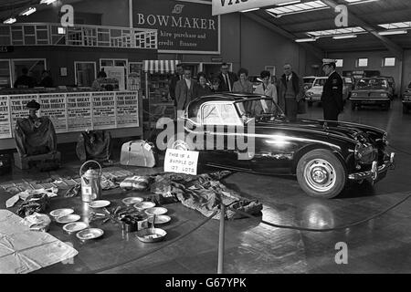 Ein Sicherheitsbeamter steht vor der Tür, als Mitglieder der Öffentlichkeit ein schwarzes Auto aus Austin Healey inspizieren, das Bruce Reynolds am 9. August 1963 gekauft hatte, am Tag nachdem die Raubbande des Great Train den Postzug in der Nähe von Cheddington, Buckinghamshire, hochgehalten hatte. Das Auto wurde auf der Leatherslade Farm gefunden und soll in Measham, Leicestershire, versteigert werden. Der Erlös aus dem Verkauf geht an eine Firma von Schadenregulierern, die die Banken vertreten. Stockfoto