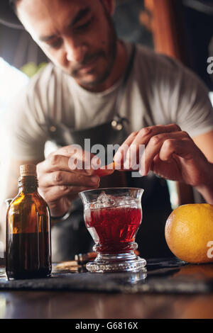 Draufsicht der Barkeeper Hände Garnierung Negroni Cocktail auf der Theke. Erstellen neue Cocktail. Stockfoto