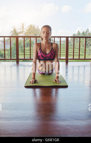 Schuss der jungen Frau, die Kobra-Pose auf tun Übung Matte am Yoga-Kurs. Fitness weiblichen Kern Strecke auf Yoga-Matte zu tun. Stockfoto