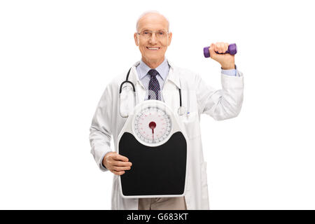 Reife Arzt hält eine Waage und eine Kurzhantel isoliert auf weißem Hintergrund Stockfoto