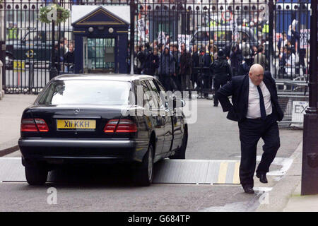 Ein Auto steckt an der Sicherheitsbarriere vor der Downing Street fest, während eine Anti-Kriegs-Demo auf dem Weg nach Whitehall vorbeifährt. Stockfoto