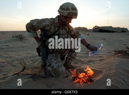 Ein Soldat des britischen 29 Commando Regiment Royal Artillery 'sanitises' sein Kit, indem er seine persönliche Post in der Kuwait-Wüste nahe der irakischen Grenze verbrennt. *..Truppen, die möglicherweise an zukünftigen Operationen beteiligt sind, desinfizieren ihre Ausrüstung, um keine Effekte einzuschließen, die dem Feind helfen könnten. Während sich die Streitkräfte in den Golfstaaten auf den Krieg zurüsten, wird US-Präsident Bush am Sonntag mit den britischen und spanischen Premierministern zusammentreffen, inmitten einer diplomatischen Sackgasse vor den Vereinten Nationen wegen der von den USA geführten Pläne zur Entwaffnung des Irak. Stockfoto