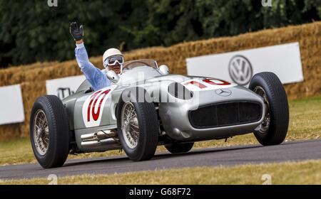 Der langjährige Rennfahrer Sir Stirling Moss winkt, als er beim Goodwood Festival of Speed bei Chichester, West Sussex, einen Mercedes Benz W196 bergauf fährt. Stockfoto