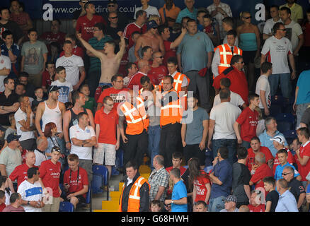 Allgemeine Ansicht der Probleme in den Ständen unter den Fans, während die Stewards einen Ventilator die Treppe hinunterführen Stockfoto