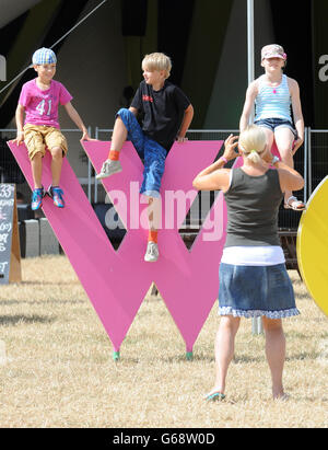 Womad Festival 2013. Kinder posieren für ein Foto auf einer Skulptur während des Womad Festivals 2013, das im Charlton Park in Wiltshire stattfand. Stockfoto