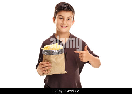 Fröhliche kleine Junge hält einen Beutel mit Kartoffelchips und darauf mit seinem Finger isoliert auf weißem Hintergrund Stockfoto