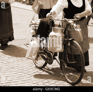 Aluminium Milchkannen transportiert auf altes Fahrrad der älteren Frau Stockfoto