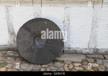 Ein alter Mühlstein steht an einer Wand. Stockfoto