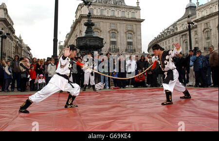 Mitglieder des Chinese State Circus treten im Piccadilly Circus im Zentrum von London für eine Menschenmenge auf, um den ersten National Circus Day zu feiern. Stockfoto