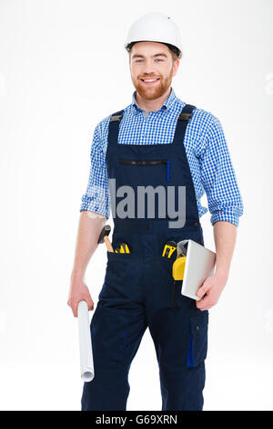 Porträt von lächelnden überzeugt junge Baumeister in Helm holding Tablet und Baupläne Stockfoto