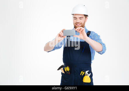 Glücklich attraktive junge Baumeister in Helm fotografieren mit smartphone Stockfoto