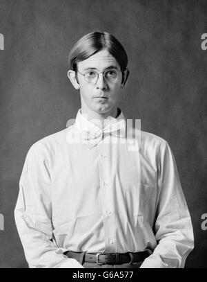 1970ER JAHRE PORTRAIT GEEKY DORKY SCHÜCHTERNE MAUERBLÜMCHEN JÜNGLING TRÄGT BRILLE WEIßES HEMD UND FLIEGE Stockfoto