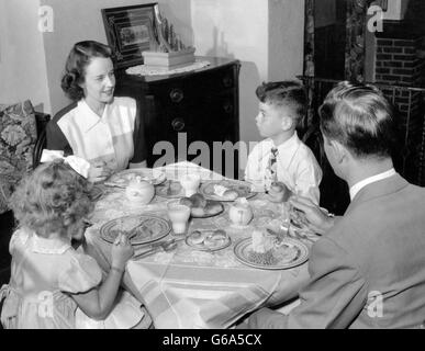 1940S 1950S FAMILIE MUTTER VATER JUNGE MÄDCHEN ESSEN ABENDESSEN AM ESSTISCH Stockfoto