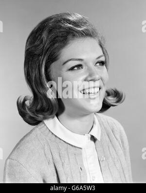 1960ER JAHREN LÄCHELNDE FRAU PORTRAIT MIT LEICHT GEZUPFTE FLIP FRISUR Stockfoto