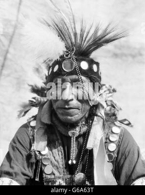1920ER JAHRE PORTRAIT INDIANISCHEN MANN VON CHEROKEE STAMM SHIRT MIT KLEINEN SPIEGELN VERZIERT Stockfoto