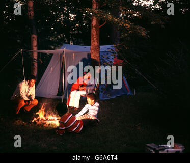 1970ER JAHREN AFROAMERIKANISCHE FAMILIE CAMPING MIT ZELT-NACHT ERSCHOSSEN AM LAGERFEUER SITZEN Stockfoto