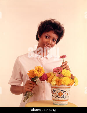 1970ER JAHRE PORTRAIT LÄCHELND AFROAMERIKANISCHE FRAU ARRANGIEREN BLUMEN Stockfoto