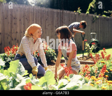 1970ER JAHRE MUTTER TOCHTER UND SOHN IM GARTEN IM HINTERHOF Stockfoto