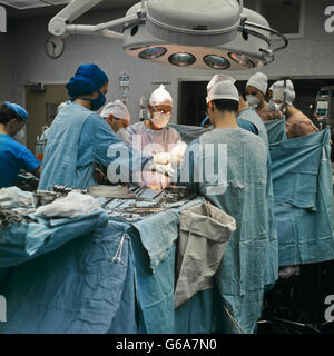 1990ER JAHREN ÄRZTE UND KRANKENSCHWESTERN DARSTELLENDE CHIRURGIE IM KRANKENZIMMER IN BETRIEB Stockfoto