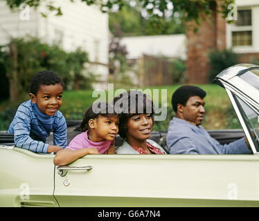 1970ER JAHRE AFRIKANISCHER AMERIKANER VIERKÖPFIGE FAMILIE REITEN IM CABRIO AUTO VATER MUTTER SOHN TOCHTER Stockfoto