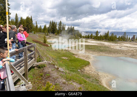 Klar, Aqua Therme mit tief Mittelbohrung, Dampf und kalkigen Küstenlinie, Menschen auf der Promenade, West Daumenbereich von Yellowstone Stockfoto