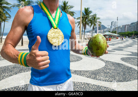 Goldmedaille Athlet stehend mit grünen Kokosnuss Coco Gelado auf der Promenade am Strand der Copacabana, Rio De Janeiro, Brasilien Stockfoto