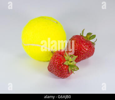 Einen grünen Tennisball mit zwei Erdbeeren Stockfoto